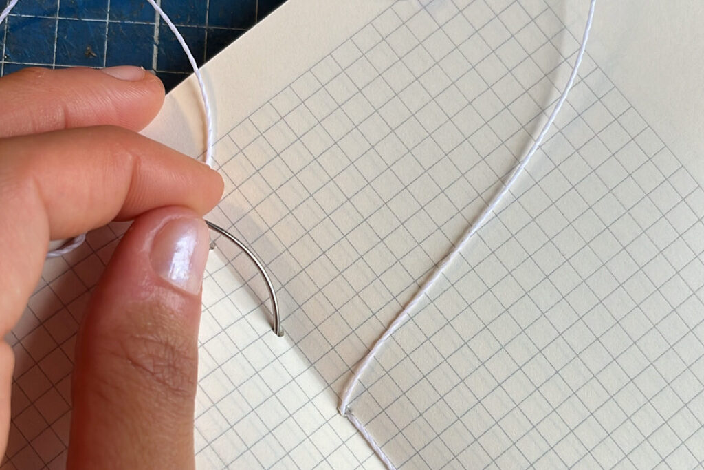 Encadernação artesanal com costura manual em linha encerada, utilizada na produção dos cadernos Juliana Chagas.