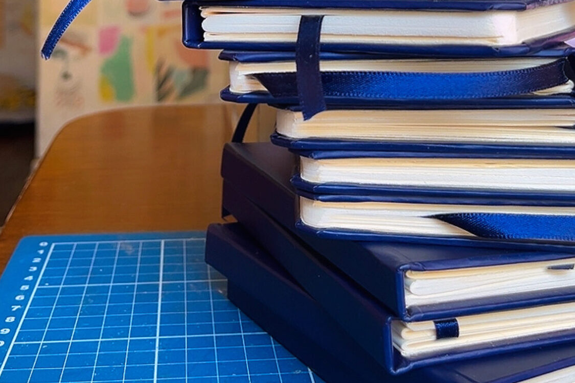 Cadernos personalizados para empresas com capa dura azul-marinho, produzidos artesanalmente pela Juliana Chagas.